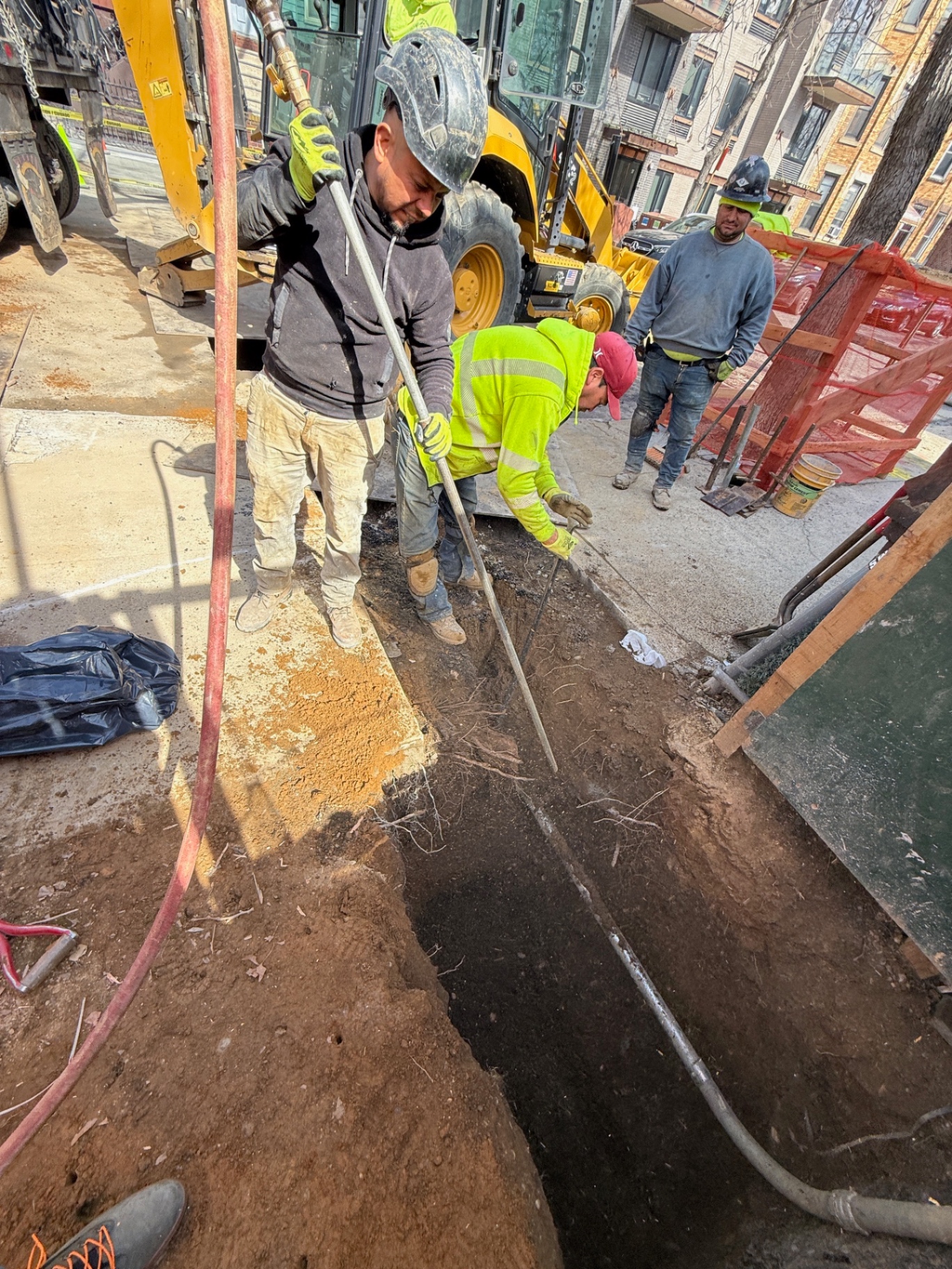 Professional arborists using pneumatic air excavation equipment to safely expose tree roots without damage during construction project